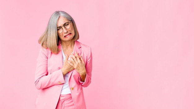 luciendo triste, lastimado y con el corazón roto, sosteniendo ambas manos cerca del corazón, llorando y sintiéndose deprimido