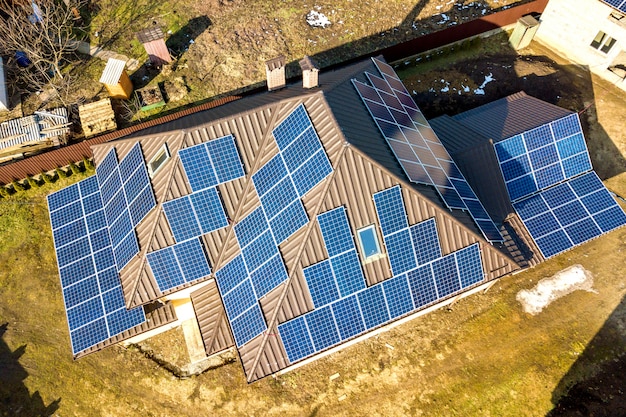 Luftansicht des neuen modernen Wohnhaushauses mit blau glänzendem Solarfoto-Voltaik-Paneelsystem auf Dach.