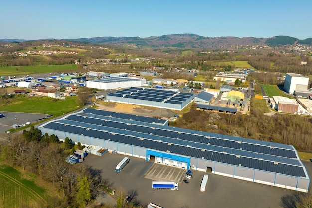 Luftansicht eines Solarkraftwerks mit blauen Photovoltaikplatten, die auf dem Dach eines Industriegebäudes montiert sind, um grünen, ökologischen Strom zu erzeugen.