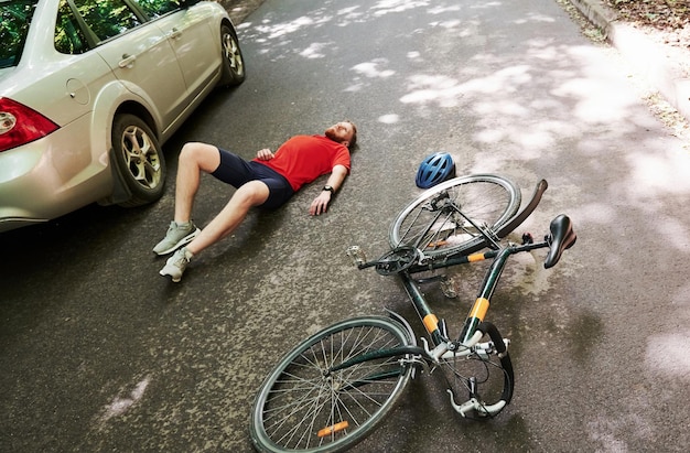 Foto luftansicht opfer auf dem asphalt fahrrad- und silberfarbener autounfall auf der straße im wald tagsüber