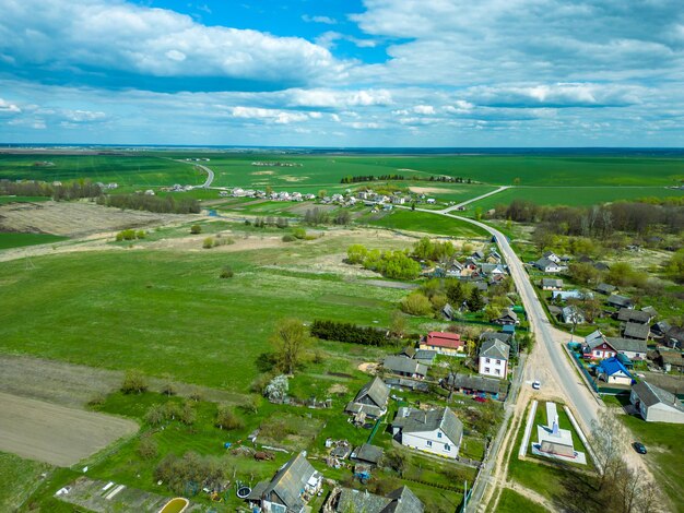 Luftansicht über ein kleines Dorf in der Nähe einer unbefestigten Straße Große mehrfarbige Felder mit verschiedenen landwirtschaftlichen Nutzpflanzen Weizenfeld aus der Vogelperspektive