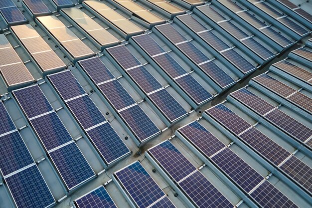 Luftansicht von blauen Photovoltaik-Solarpanelen, die auf dem Dach eines Industriegebäudes montiert sind, um grünen, ökologischen Strom zu erzeugen.