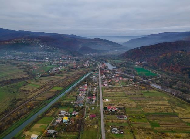Luftansicht von oben nach unten über das Dorf in der Nähe des Berges in der Nähe des Berges aus der Luft von oben nach unten über die Landschaft von Karpaty