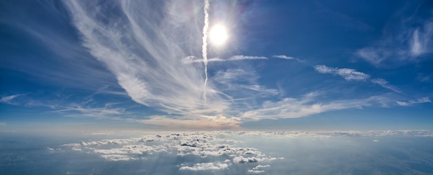 Luftaufnahme aus dem Flugzeugfenster in großer Höhe der Erde, bedeckt mit einer weißen, dünnen Schicht aus nebligem Dunst und fernen Wolken