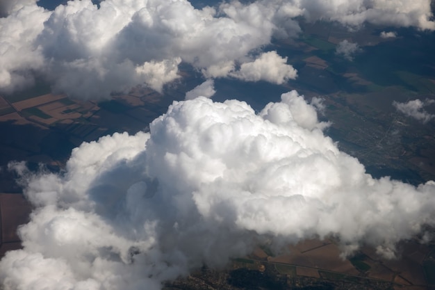 Luftaufnahme aus dem Flugzeugfenster von weißen geschwollenen Wolken an einem sonnigen Tag.