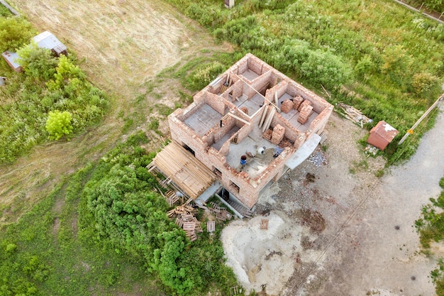 Luftaufnahme der Baustelle für zukünftiges Haus, Ziegelkellerboden und Ziegelstapel für den Bau.