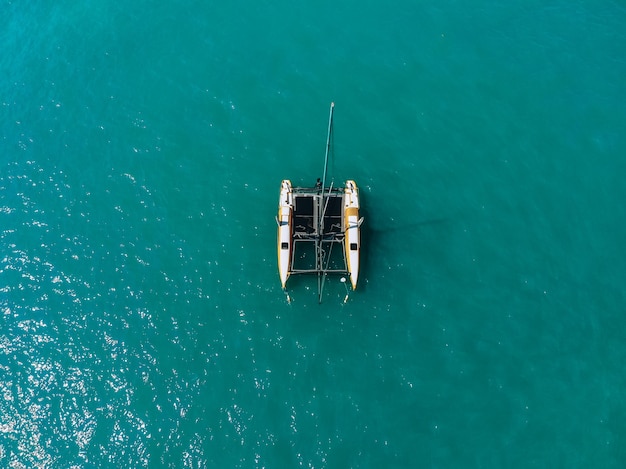 Luftaufnahme der erstaunlichen tiefblauen Lagune an heißen Sommertagen mit Segelkatamaran über das Meer. Ansicht von oben.