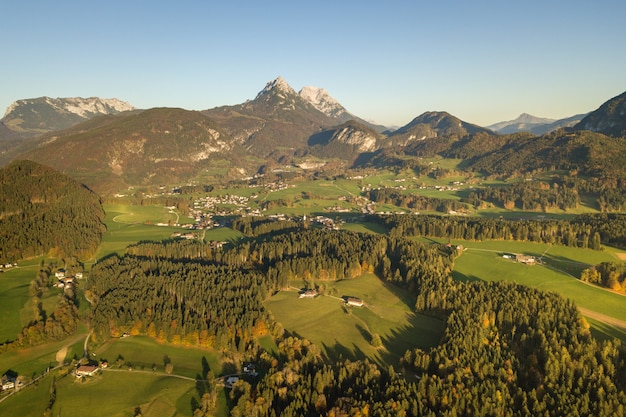 Luftaufnahme der grünen Wiesen mit Dörfern und Wald in den österreichischen Alpenbergen.