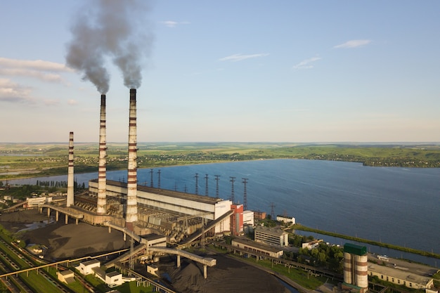 Luftaufnahme der hohen Rohre des Kohlekraftwerks mit schwarzem Rauch, der die umweltverschmutzende Atmosphäre nach oben bewegt.