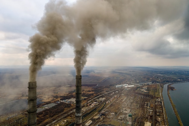 Luftaufnahme der hohen Rohre des Kohlekraftwerks mit schwarzem Rauch, der die umweltverschmutzende Atmosphäre nach oben bewegt.