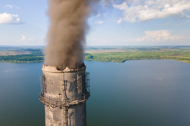 Luftaufnahme der hohen Rohre des Kohlekraftwerks mit verschmutzender Atmosphäre des schwarzen Schornsteins. Stromproduktion mit fossilem Brennstoffkonzept.