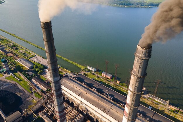 Luftaufnahme der hohen Rohre des Kohlekraftwerks mit verschmutzender Atmosphäre des schwarzen Schornsteins. Stromproduktion mit fossilem Brennstoffkonzept.