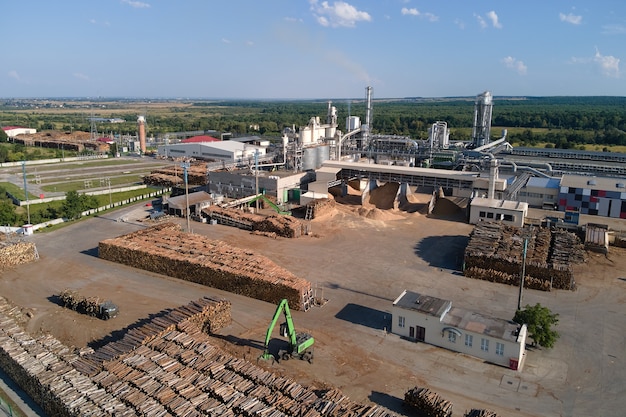 Luftaufnahme der Holzverarbeitungsfabrik mit Holzstapeln im Werksfertigungshof.