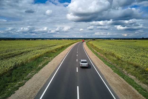 Luftaufnahme der Intercity-Straße zwischen grünen landwirtschaftlichen Feldern mit schnell fahrendem Auto Draufsicht von der Drohne des Autobahnverkehrs