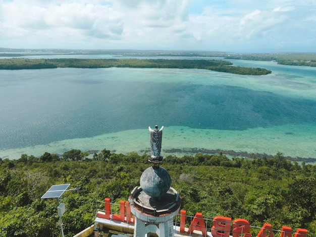 Luftaufnahme der Jesus-Statue mit wunderschönem Blick auf den Strand auf einer kleinen Insel. Maluku, Indonesien - Juli 2022