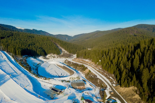 Luftaufnahme der Landschaft von Ski- und Snowboardhängen durch Kiefern, die zum Winterresort in den Karpaten hinuntergehen