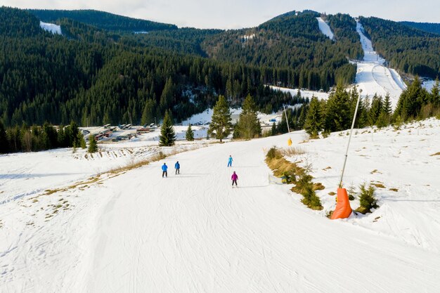 Luftaufnahme der Landschaft von Ski- und Snowboardhängen durch Kiefern, die zum Winterresort in den Karpaten hinuntergehen.