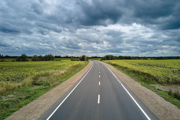 Luftaufnahme der leeren Intercity-Straße zwischen grünen landwirtschaftlichen Feldern Draufsicht von der Drohne der Autobahnfahrbahn