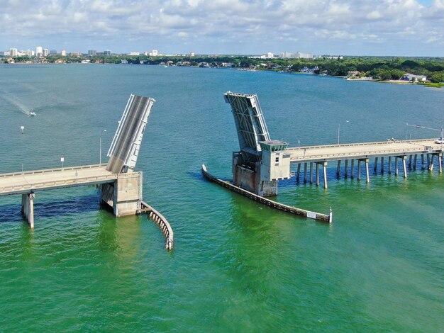 Luftaufnahme der offenen Straßenbrücke, die den Ozean mit einem kleinen Boot überquert
