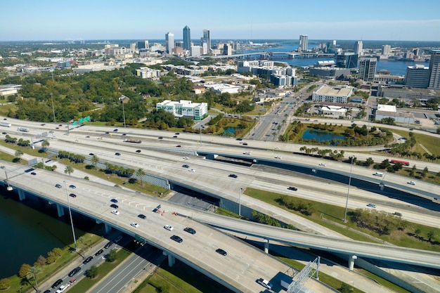 Luftaufnahme der Stadt Jacksonville mit hohen Bürogebäuden und amerikanischer Autobahnkreuzung mit schnell fahrenden Autos und Lastwagen USA-Transportinfrastrukturkonzept