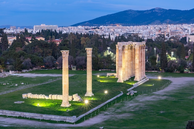 Luftaufnahme der Stadt mit Ruinen und Säulen des Tempels des Olympischen Zeus bei Nacht, Athen, Griechenland