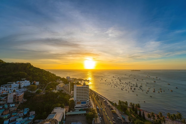 Luftaufnahme der Stadt Vung Tau mit wunderschönem Sonnenuntergang und so vielen Booten Panoramablick auf die Küste von Vung Tau von oben mit Wellen, Küstenstraßen, Kokospalmen und dem Berg Tao Phung in Vietnam