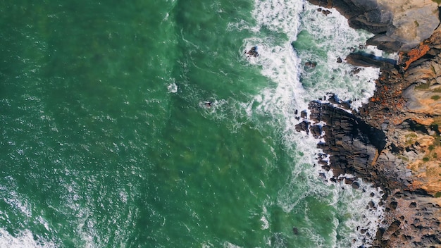 Luftaufnahme der steinigen Küste, die von stürmischen Meereswellen umspült wird, die Klippen plätschern