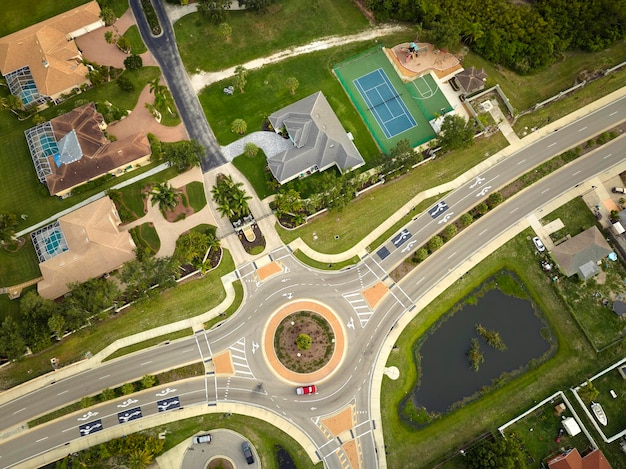 Luftaufnahme des amerikanischen Vorortsgebiets mit Landstraßen-Kreisverkehrkreuzung mit fahrendem Autoverkehr Kreisverkehrskreuzung in Florida