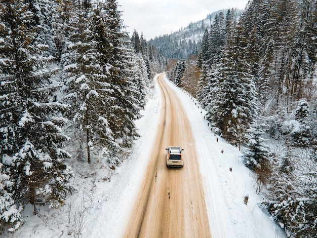 Luftaufnahme des Autos auf verschneiter Straße in der Wintersaison der Berge