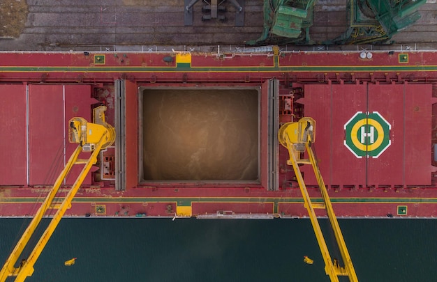 Luftaufnahme des Frachtschiffs Massengutfrachter wird bei Sonnenuntergang mit Weizenkorn im Hafen beladen