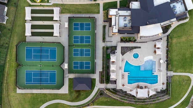 Luftaufnahme des großen Tennisplatz-Schwimmbads im Freizeitzentrum der Gemeinde mit Villen