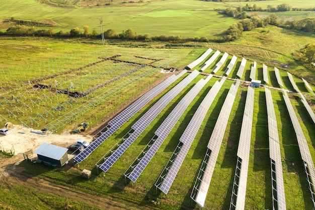 Luftaufnahme des im Bau befindlichen Solarkraftwerks auf der grünen Wiese. Montage von Elektropaneelen zur Erzeugung sauberer ökologischer Energie.