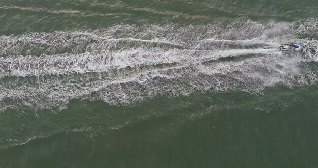 Luftaufnahme des Jetskis, der Spaß beim Springen eines wellenreitenden Jetskis im schwimmenden Ozean hat