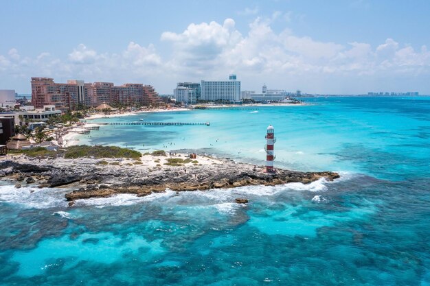 Luftaufnahme des Leuchtturms von Punta Cancun. Der mit weißen und roten Streifen geschmückte Leuchtturm befindet sich in einem felsigen Gebiet.