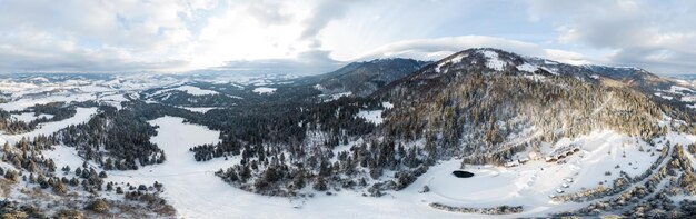 Luftaufnahme des majestätischen Sonnenaufgangs in den Bergen. Das Tal zwischen den Bergen ist mit Nebel bedeckt und wird von den warmen Strahlen der aufgehenden Sonne beleuchtet. Berge mit natürlichem Wald bedeckt