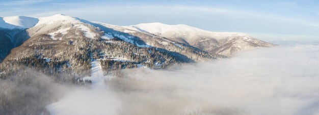 Luftaufnahme des majestätischen Sonnenaufgangs in den Bergen. Das Tal zwischen den Bergen ist mit Nebel bedeckt und wird von den warmen Strahlen der aufgehenden Sonne beleuchtet. Berge mit natürlichem Wald bedeckt