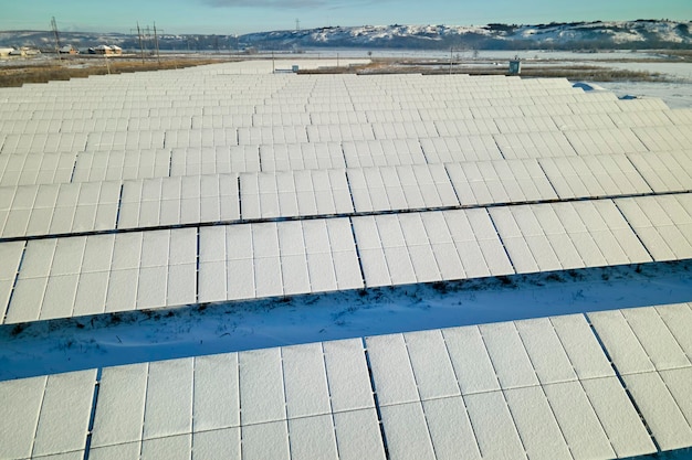 Luftaufnahme des schneebedeckten nachhaltigen Kraftwerks mit Reihen von Photovoltaikmodulen zur Erzeugung sauberer elektrischer Energie Geringe Effektivität von erneuerbarem Strom im nördlichen Winter