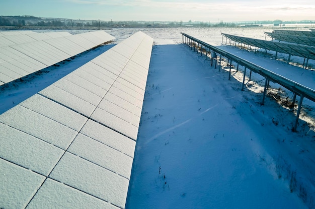 Luftaufnahme des schneebedeckten nachhaltigen Kraftwerks mit Reihen von Photovoltaikmodulen zur Erzeugung sauberer elektrischer Energie Geringe Effektivität von erneuerbarem Strom im nördlichen Winter