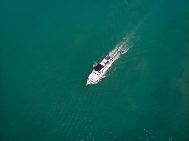 Luftaufnahme des Schnellboots und eines Bootes dahinter, das nahe der Küste von Thailand segelt, weiße Spur auf dem Wasser; Schiffe Konzept.