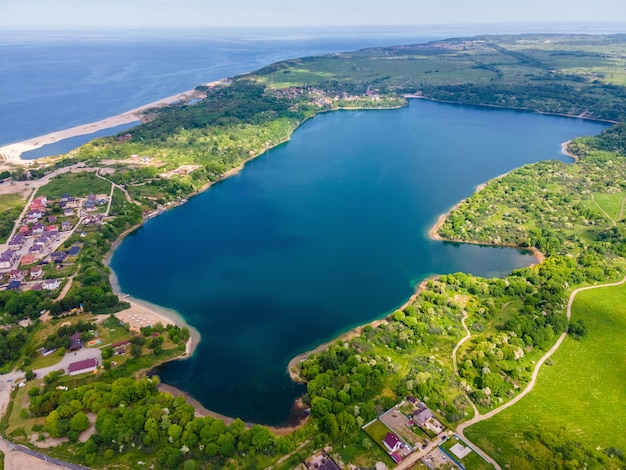 Luftaufnahme des Sees an der Meeresküste und des Waldes mit Drohne an der Ostsee, Yantarny, Russland