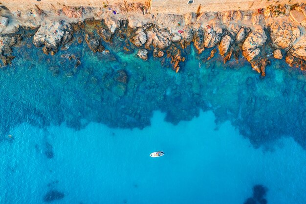 Foto luftaufnahme des strandes mit steinen und felsen allein boot in der adria bei sonnenuntergang im sommer draufsicht auf yacht im transparenten blauen wasser reisen in kroatien naturhintergrund landschaft mit meer