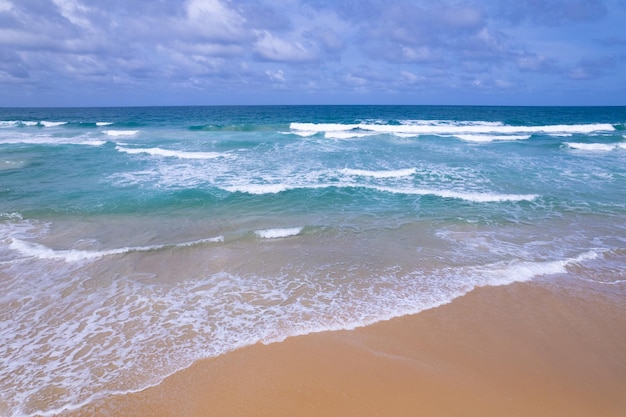 Luftaufnahme des Strandmeeres und der Wellen, die in der Sommersaison am Sandstrand abstürzen Erstaunlicher Meeresstrand mit Meereswellenschäumen Schöne Draufsicht auf die schöne Meeresoberfläche Konzept Urlaub Sommer Hintergrund