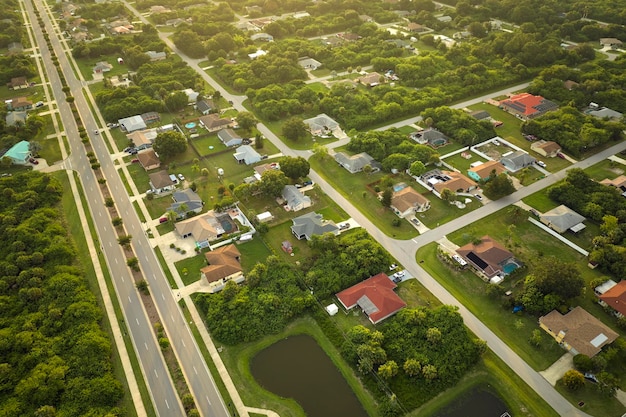 Luftaufnahme des Straßenverkehrs mit fahrenden Autos in einer amerikanischen Vorstadtlandschaft mit Privathäusern zwischen grünen Palmen in Floridas ruhiger Wohngegend