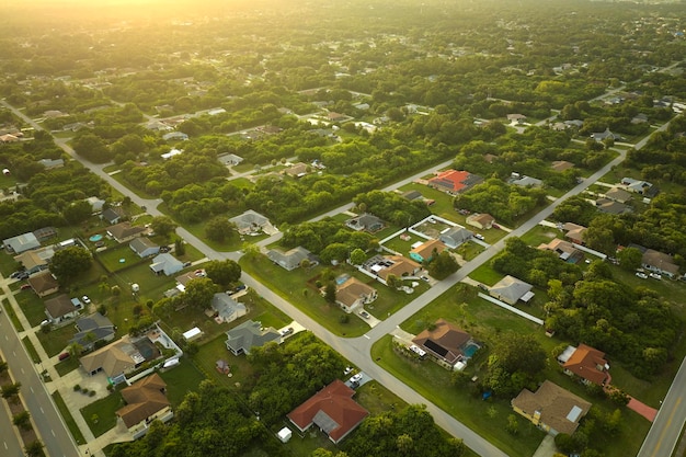 Luftaufnahme des Straßenverkehrs mit fahrenden Autos in einer amerikanischen Vorstadtlandschaft mit Privathäusern zwischen grünen Palmen in Floridas ruhiger Wohngegend