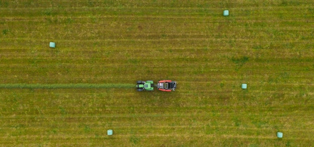 Luftaufnahme des Traktors, der im Sommer grünes Feld mäht. Drohnenschuss