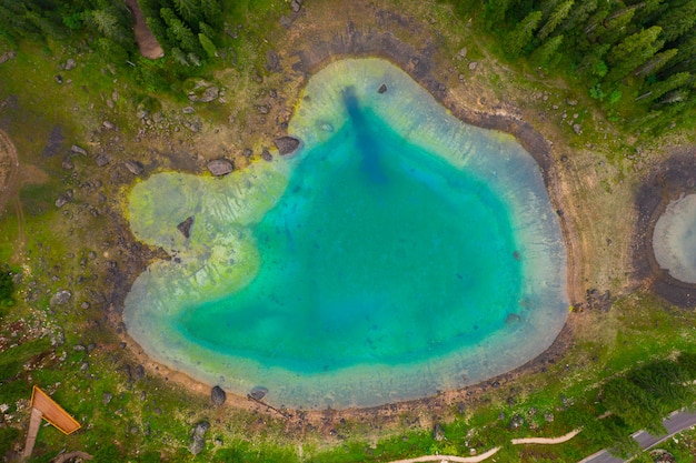 Luftaufnahme des türkisblauen Wassers des Carezza-Sees in den Alpendolomiten. Lago di Karersee in der Nähe von Tannenwald.