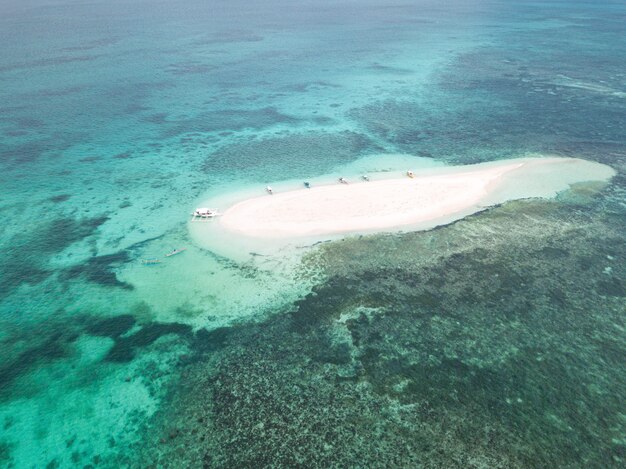 Luftaufnahme einer kleinen Sandinsel, umgeben von Wasser mit ein paar Booten