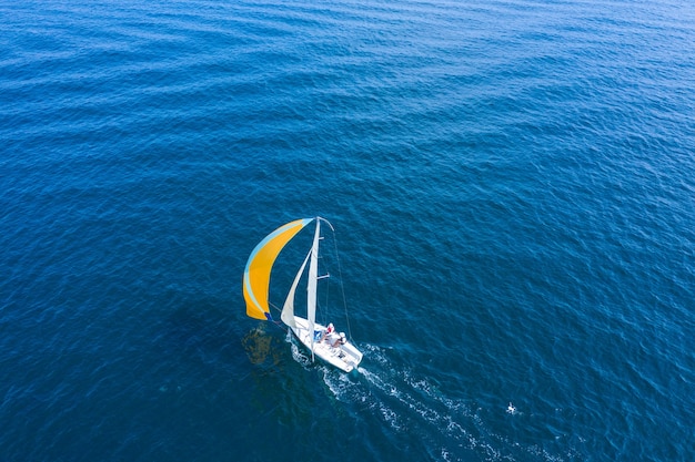 Luftaufnahme einer schönen weißen Segelyacht mit einem farbigen Segel.