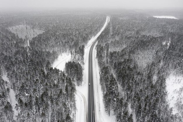 Luftaufnahme einer Straße durch einen schneebedeckten Kiefernwald, Karelien, Russland