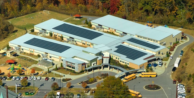 Luftaufnahme eines amerikanischen Schulgebäudes mit einem mit Photovoltaik-Solarpanelen bedeckten Dach für die Stromerzeugung
